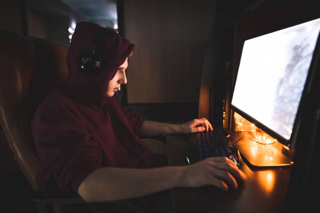 Ґеймер грає за комп'ютером у ігрових навушниках